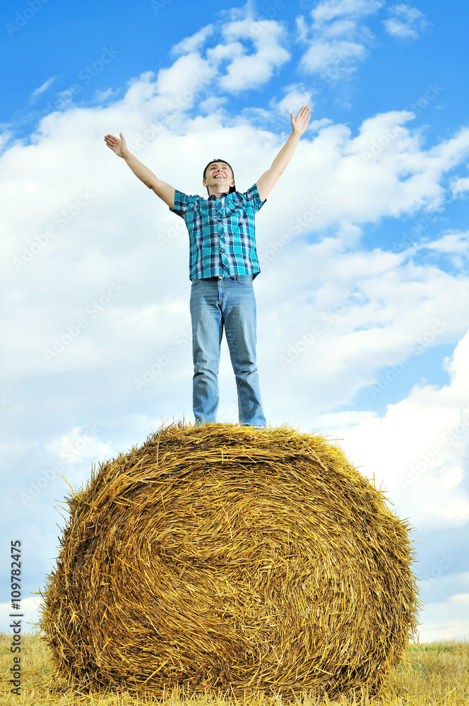 man on a stack of straw against a field man on a stack of straw against a field