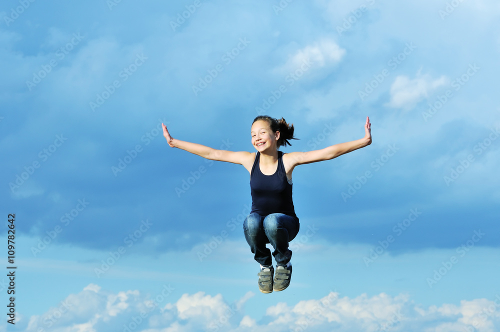 beautiful girl in gymnastic jump against blue sky