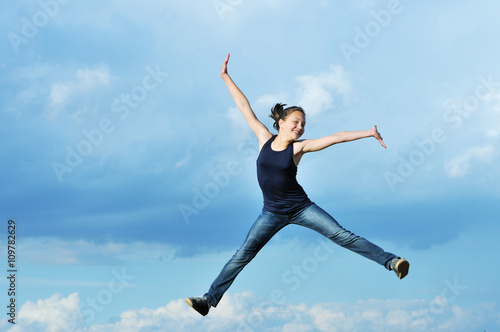 Fototapeta Naklejka Na Ścianę i Meble -  beautiful girl in gymnastic jump against blue sky