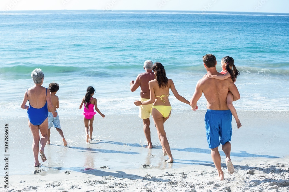 Cute multi generation family running in the sea