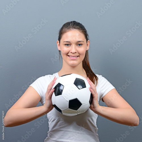 Portrait of girl holding football against gray background