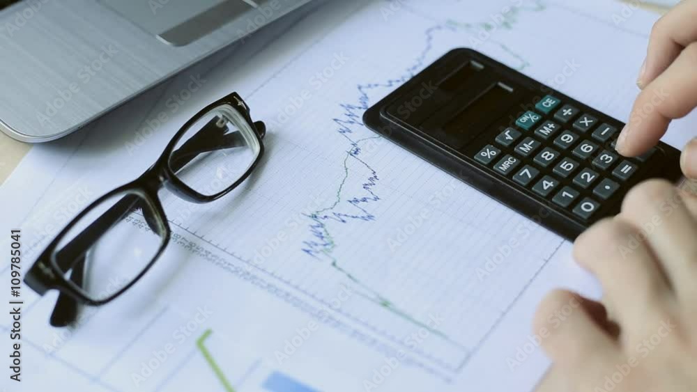 Close-up Person Hands Analyzing Financial Report With Calculator