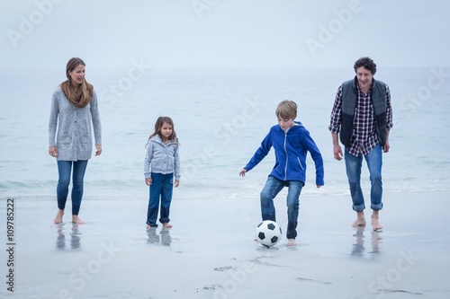 Family playing soccer at sea shore