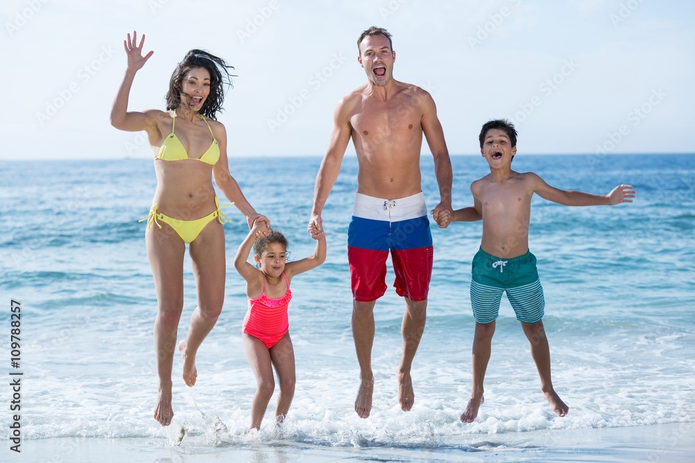 Family in swimwear jumping at sea shore Family in swimwear jumping at sea shore