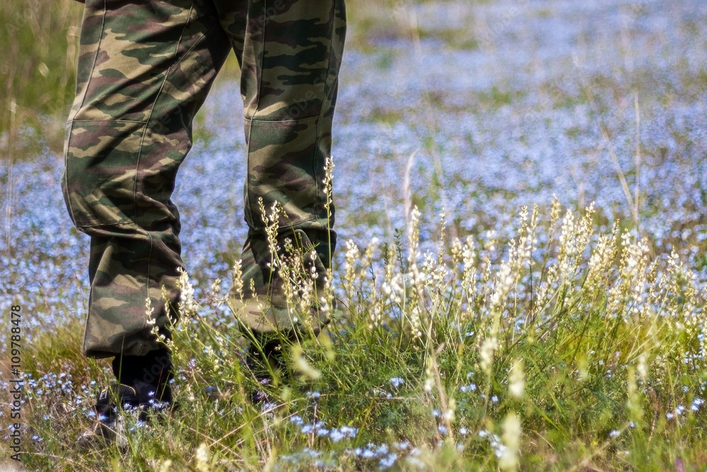 Man in camouflage uniform standing on flower field Man in camouflage uniform standing on flower field