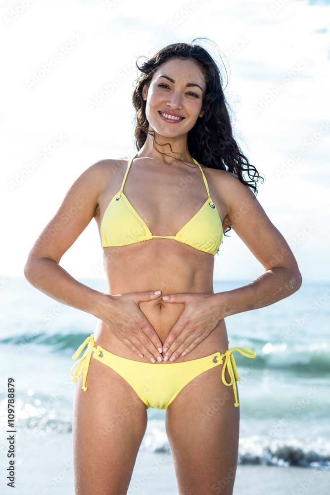 Portrait of happy woman in bikini touching belly