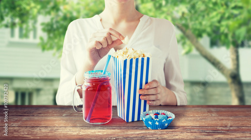 woman eating popcorn with drink in glass mason jar