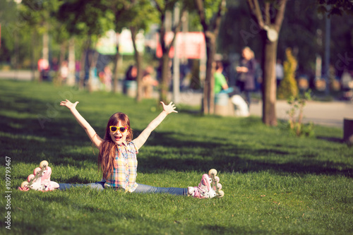 girl wearing roller skates sitting on grass in the park.