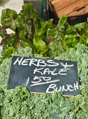 Herbs and kale for sale at an outdoor farmers market 