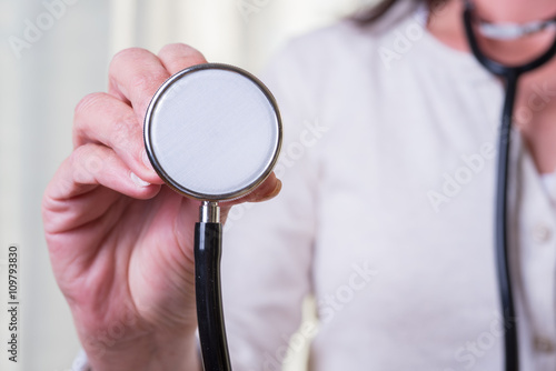 female doctor is holding stethoscope into the camera