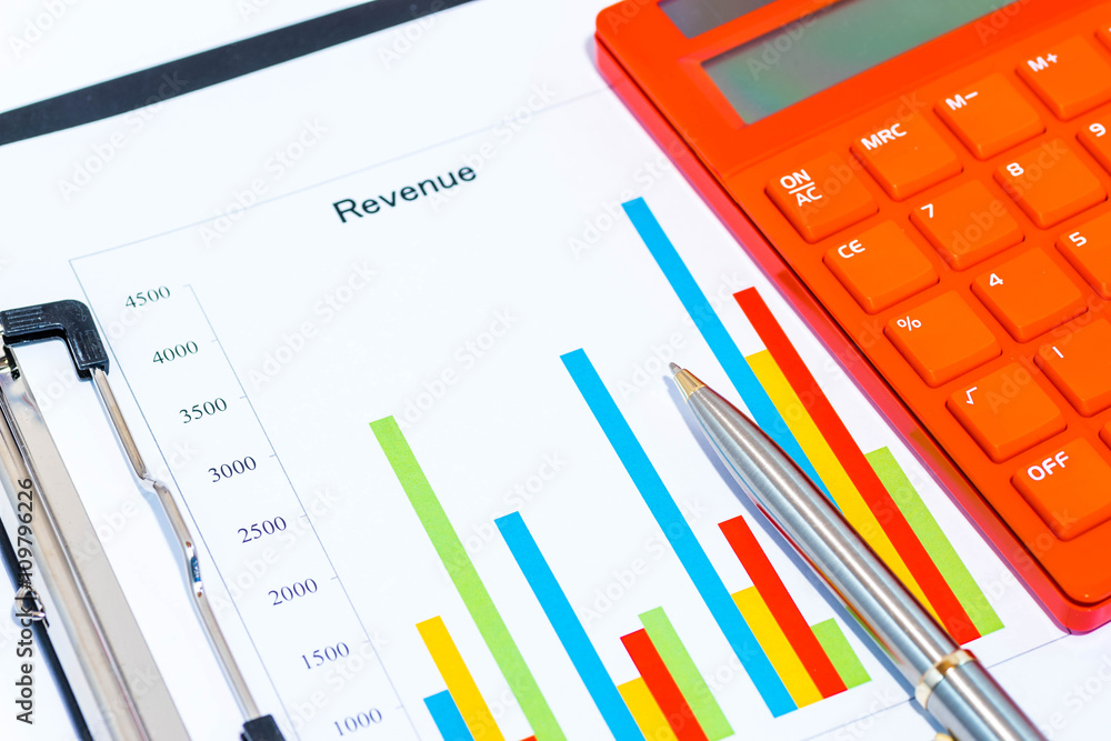 Red electronic calculator on spreadsheet with black clipboard