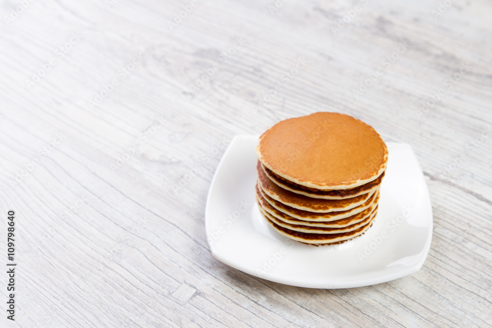 Tasty pancake on a white plate, wooden background, maple syrup Tasty pancake on a white plate, wooden background, maple syrup