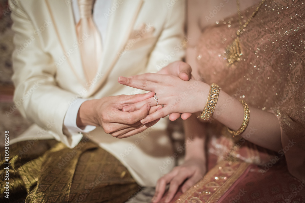 Thai groom wearing wedding ring for her bride