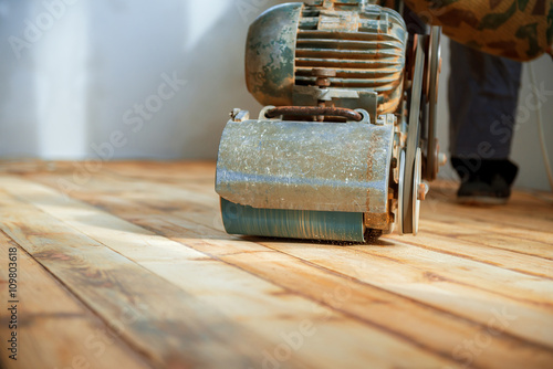 Worker polishing parquet floor with grinding machine