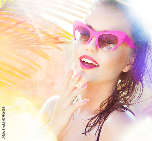 Colorful summer portrait of happy young attractive woman wearing wet sunglasses. wet hair beauty and fashion concept. natural bokeh and light effect photo