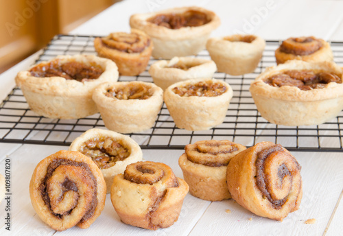 Freshly baked butter tarts and cinnamon rolls on a cooling rack