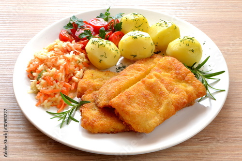 ryba smażona z ziemniakami, surówką i pomidorem