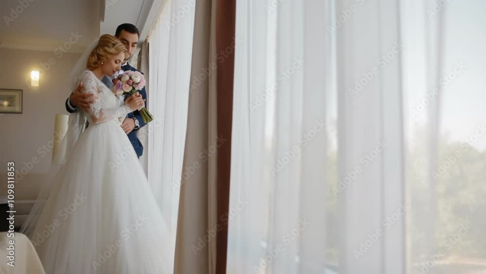 Happy bride and groom stand near the window Happy bride and groom stand near the window