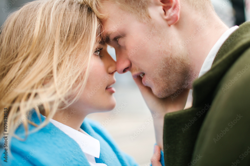 Young happy blonde couple kissing and hugging on city street Young happy blonde couple kissing and hugging on city street