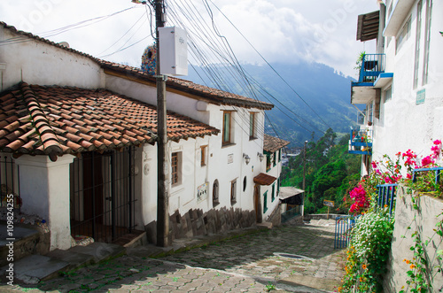 Charming village located outside Quito Ecuador with bridgestone road leading down to dome tower of spanish colonial building photo