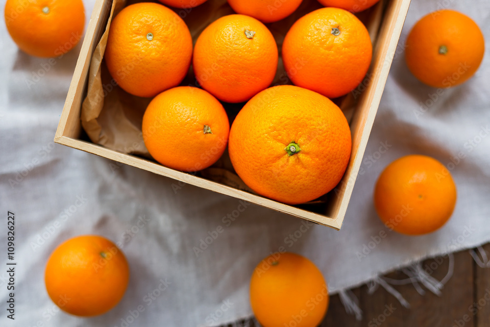 Box full of fresh oranges. Fruit harvest on rustic wooden table.