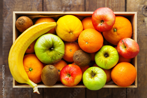 Box full of fresh fruits. Fruit harvest - apples, oranges, lemon, banana, kiwi.