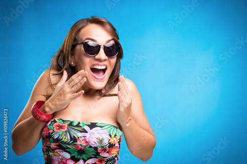 Surprised woman with sunglasses shouting over blue background