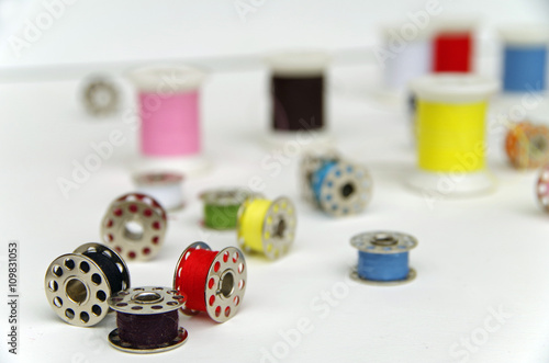 Foto Metal bobbin spools with colorful thread arranged in white background