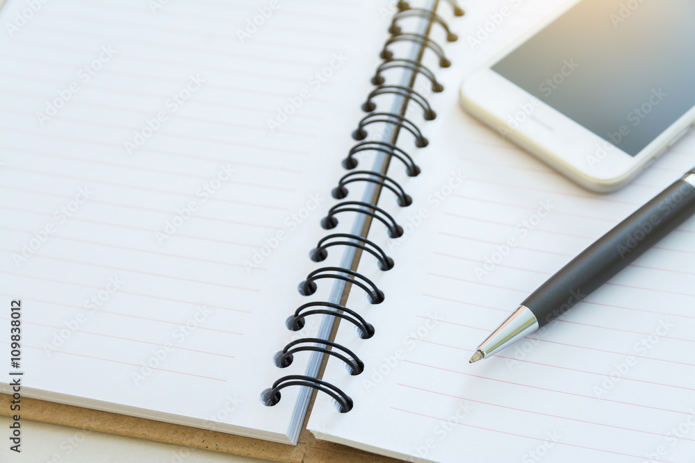 pen and smartphone on open blank notebook pen and smartphone on open blank notebook