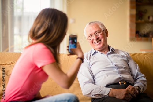 Grandchild photographing grandfather on her phone
