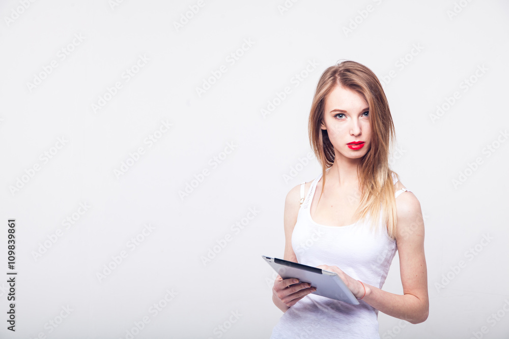 Beautiful happy blond girl in white T shirt and jeans smiling looking at tablet computer with copy place on white background on white background Beautiful happy blond girl in white T shirt and jeans smiling looking at tablet computer with copy place on white background on white background