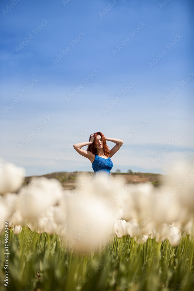 Woman in tulips flowers posing in blue dress Woman in tulips flowers posing in blue dress