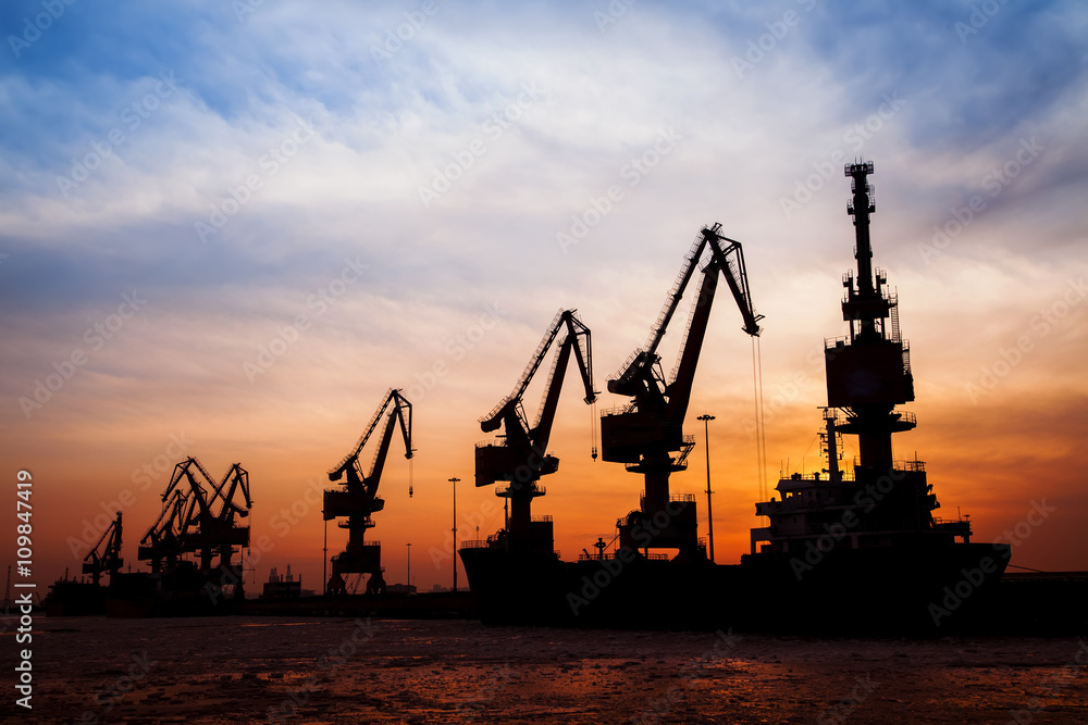 In the evening, the silhouette of port cranes