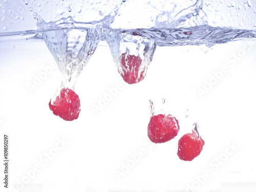 four raspberries falling on water