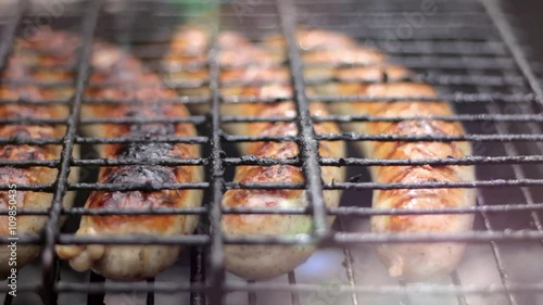 Bratwurst sausages cooking on a wood barbecue.