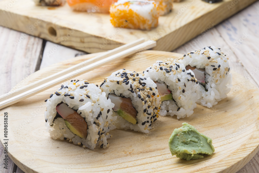 Different Sushi rolls,wasabi and ginger on a plate on wooden bac Different Sushi rolls,wasabi and ginger on a plate on wooden bac