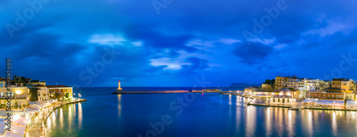 Picturesque panoramic view of old harbour of Chania with Lighthouse and Kucuk Hasan Pasha Mosque during twilight blue hour, Crete, Greece