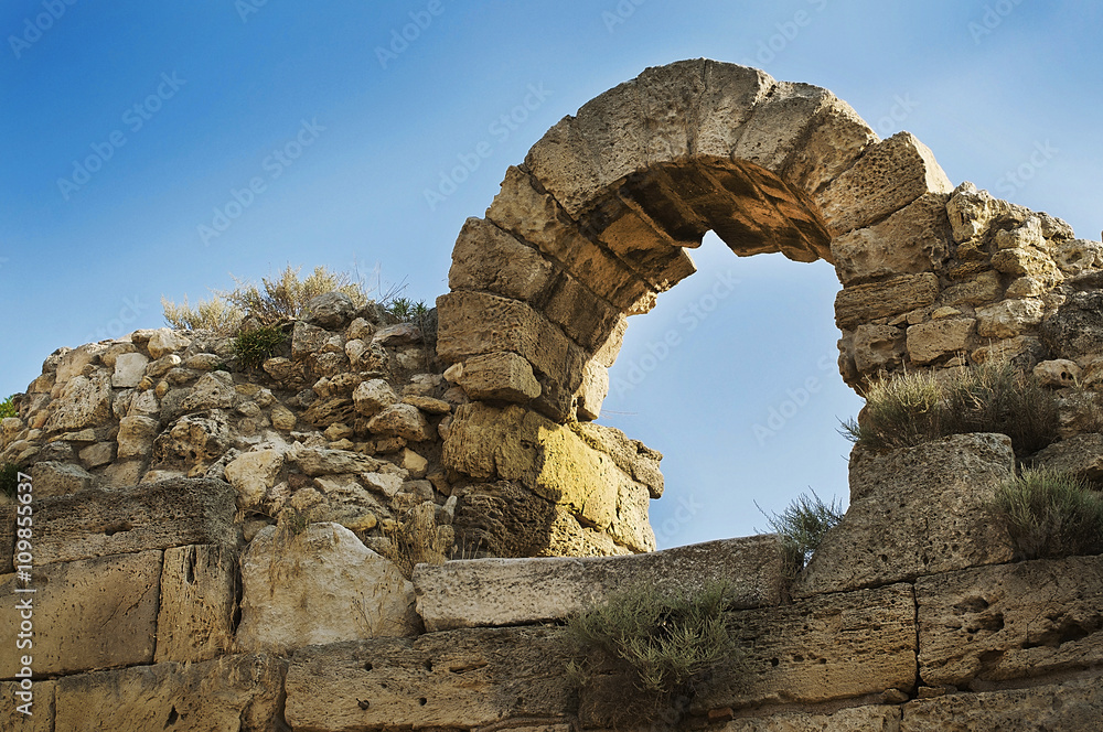 Ruins of ancient Greek sandstone wall with an arch window opening