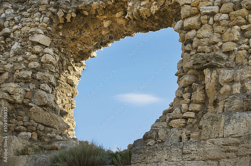 Ruins of ancient Greek sandstone wall with big hole
