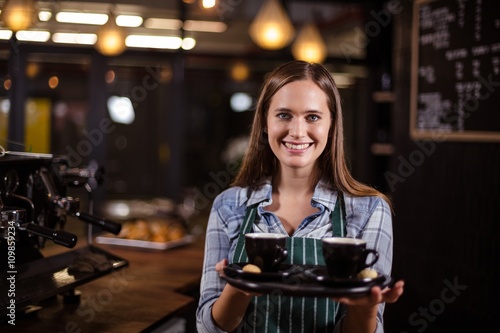 Smiling barista holding tray with coffees