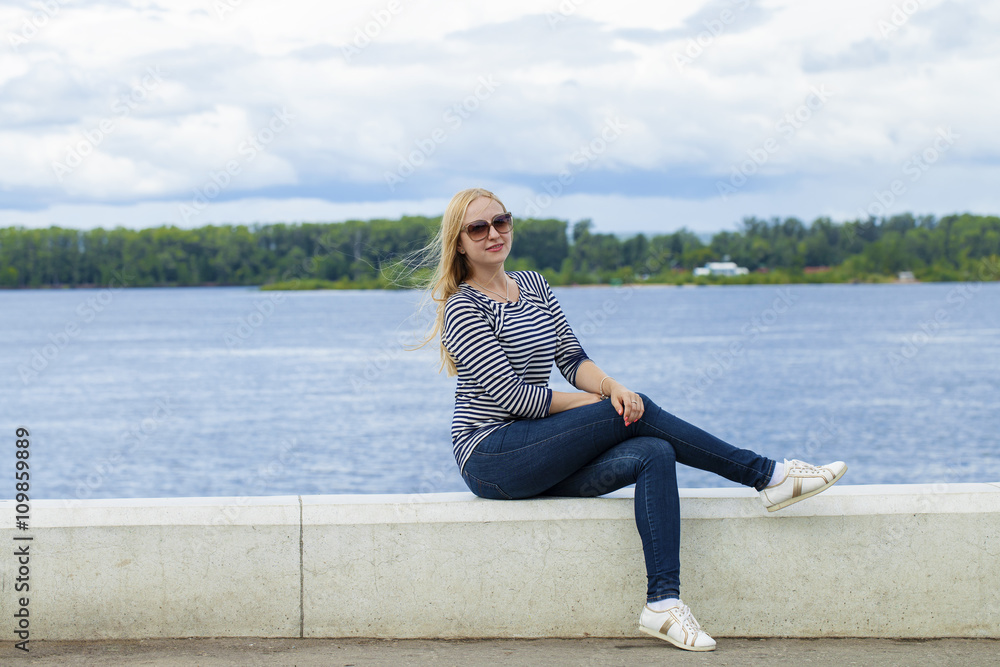 Young beautiful woman in blue jeans sitting in summer street par Young beautiful woman in blue jeans sitting in summer street par