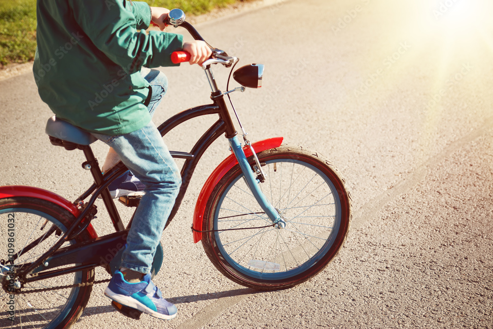 Naklejka premium child on a bicycle at asphalt road