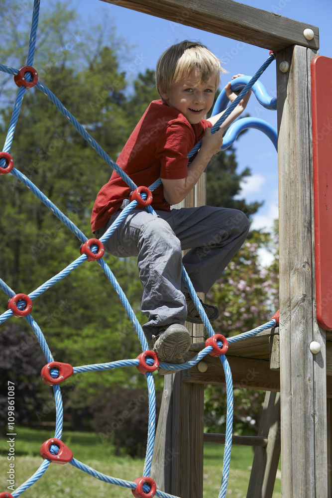 Happy child boy climbed on top of the rope web on playground Happy child boy climbed on top of the rope web on playground