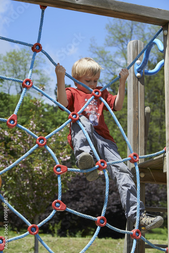 Happy child boy climbed on top of the rope web on playground