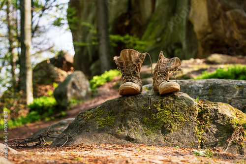Well-worn hiking boots, unlaced and muddy on the forest floor. Tourism concept. photo