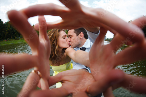 Man and woman kiss reaching their hands out to the camera