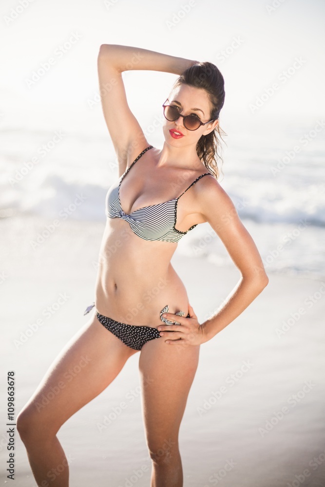 Portrait of glamorous woman in bikini and sunglasses standing