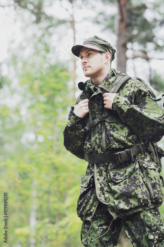 young soldier with backpack in forest