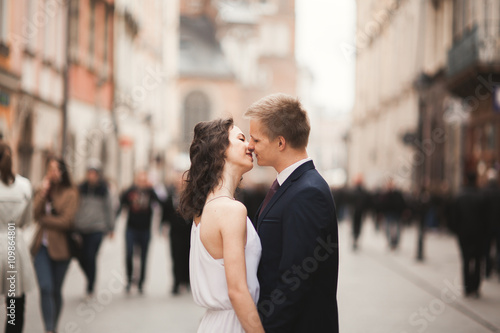 Gorgeous wedding couple  bride  groom kissing and hugging standing in the crowd