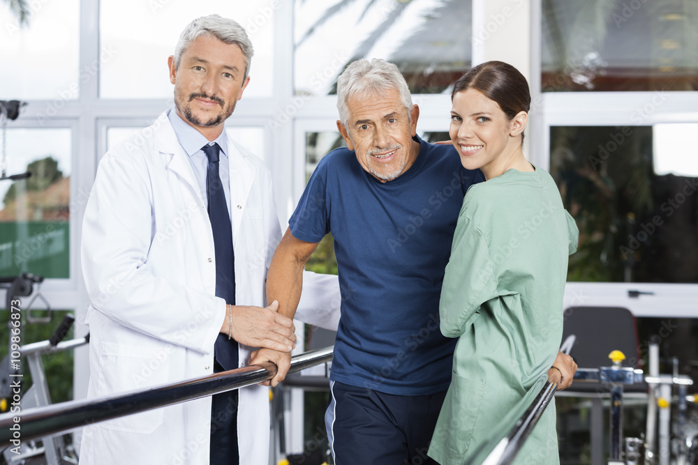 Fototapeta premium Confident Physiotherapists With Senior Patient In Fitness Studio